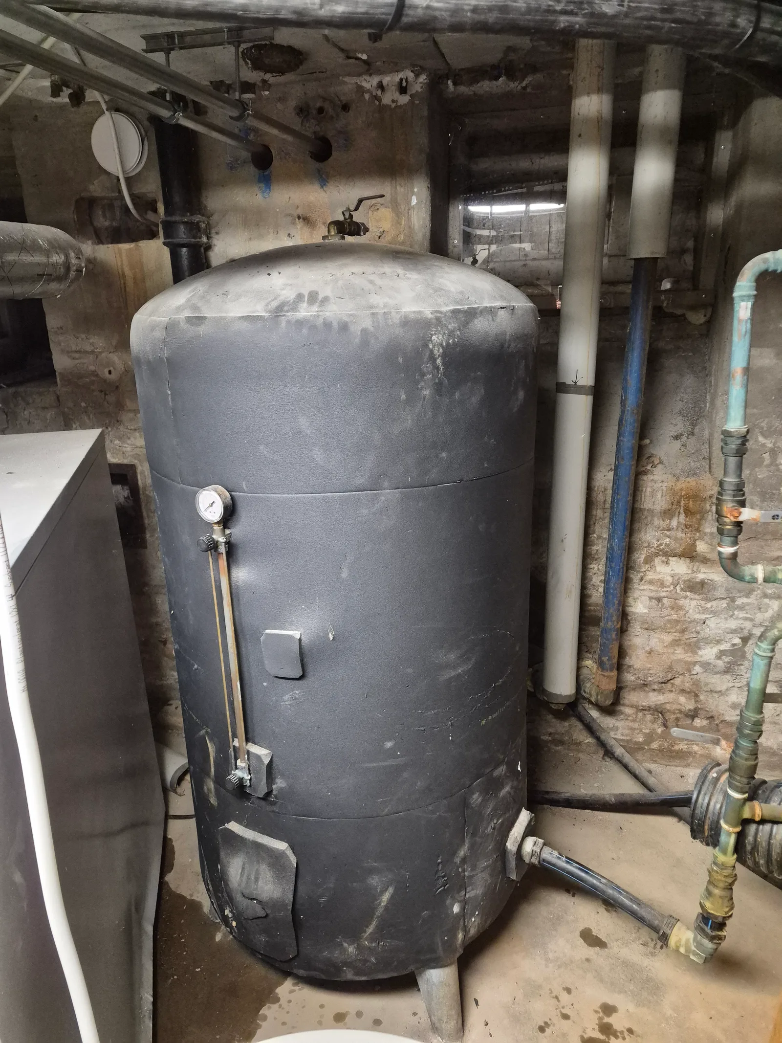 Stor varmvattenberedare installerad i ett pannrum med isolerade anslutningar
